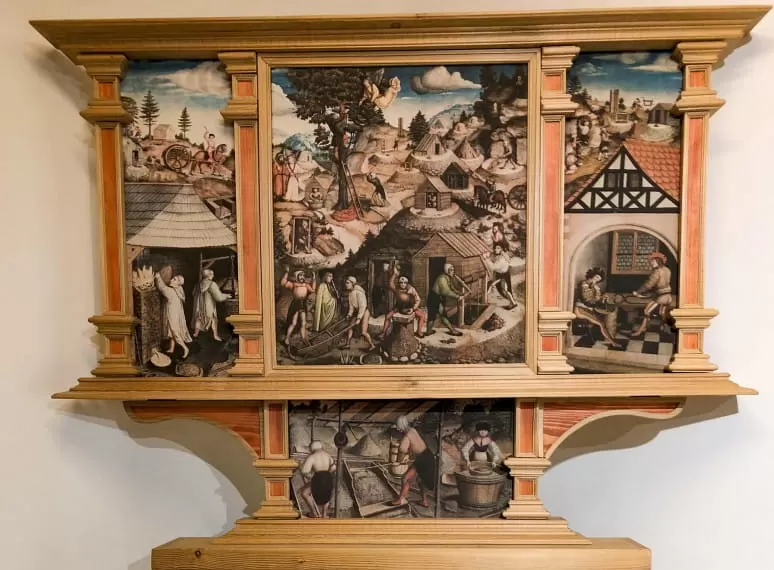 Historischer Altaraufsatz mit detaillierten Szenen aus dem Leben und Arbeiten der Bergleute, in einem kunstvoll gestalteten Holzrahmen. 