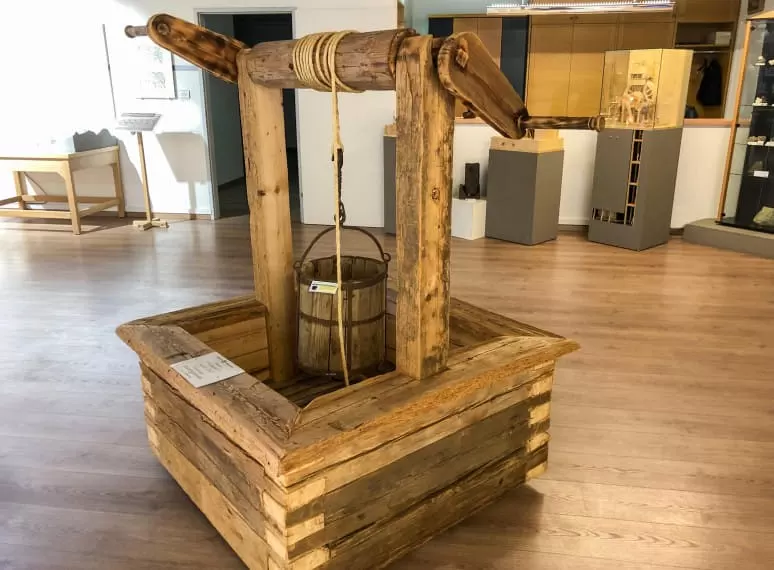 Holzbrunnen mit Eimer und Kurbel im Ausstellungsraum des Rerobichl Bergbaumuseums in Oberndorf. 