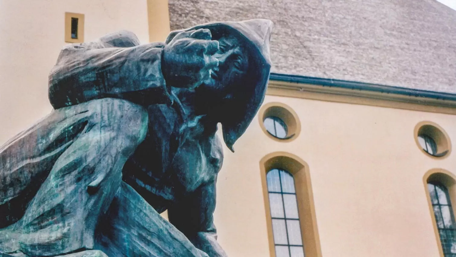 Bronzestatue eines knienden Bergarbeiters vor der Kirche in Fieberbrunn.